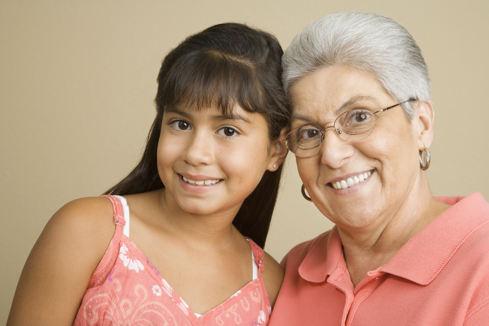 Studio shot of Hispanic grandmother and granddaughter smiling